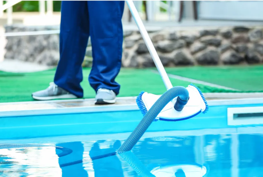 Homeowner with a vacuum doing pool maintenance.